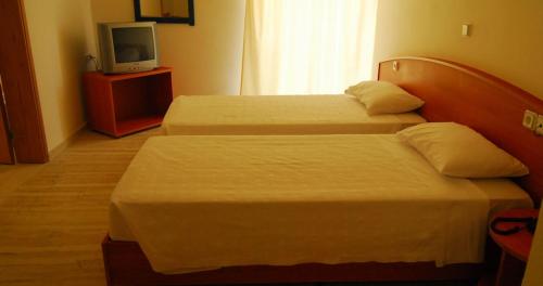 a hotel room with two beds and a television at Cleopatra Hotel in Kanali