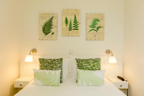 a bedroom with a bed with four leaves posters on the wall at Hotel Nova Sintra in Sintra