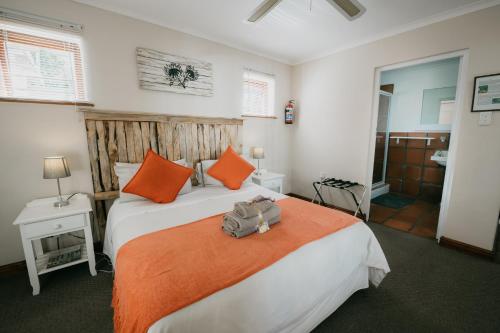a bedroom with a large bed with orange pillows at The Village Lodge in Stormsrivier
