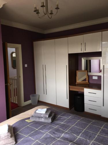 a bedroom with a bed and white cabinets and a mirror at Hillhouse in Edinburgh