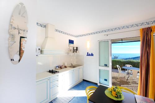 a kitchen with white cabinets and a table and a view at Poggio dei Gorleri in Diano Marina