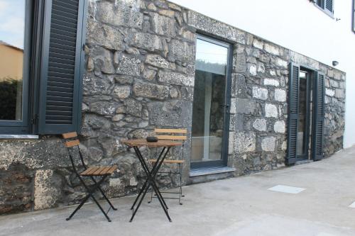 two chairs sitting in front of a stone building at Refúgio in Horta