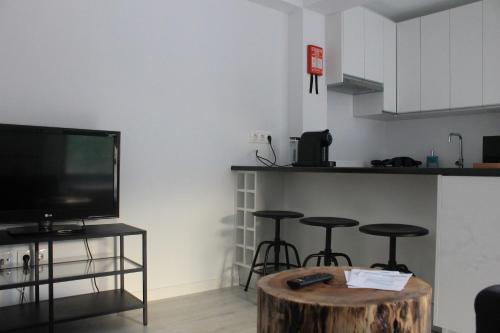 a living room with a flat screen tv and a wooden stump coffee table at Refúgio in Horta