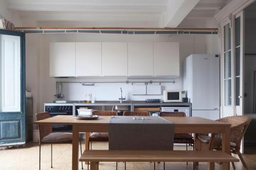 una cocina con mesa y sillas y una cocina con armarios blancos. en Apartment E.CO. Home Tarragona, en Tarragona