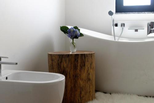 a bathroom with a vase of flowers on a wooden stump at Refúgio in Horta