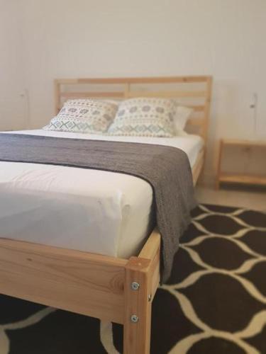 a bedroom with a wooden bed with pillows and a rug at Refúgio in Horta