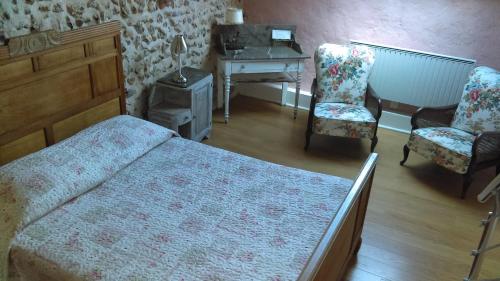 1 Schlafzimmer mit einem Bett, 2 Stühlen und einem Schreibtisch in der Unterkunft Les 3 roses in Villeneuve-sur-Yonne