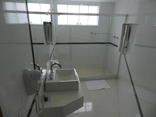 a white bathroom with a sink and a shower at Casablanca Center Hotel in Petrópolis