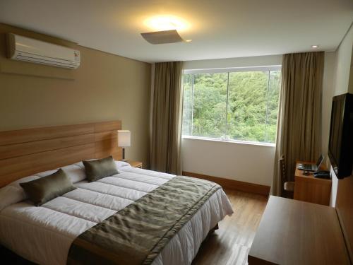 a bedroom with a bed and a large window at Casablanca Center Hotel in Petrópolis