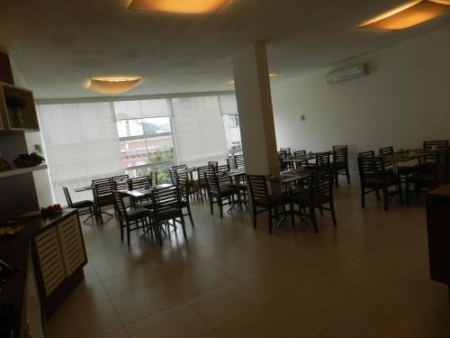 a dining room with chairs and tables and a large window at Casablanca Center Hotel in Petrópolis