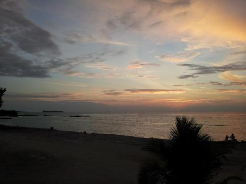 a sunset at the beach with people on the beach at Arora Inn in Maafushi