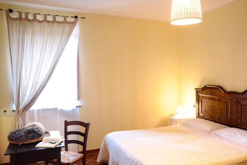 a bedroom with a bed and a table and a window at Agriturismo Monastero Di San Biagio in Nocera Umbra