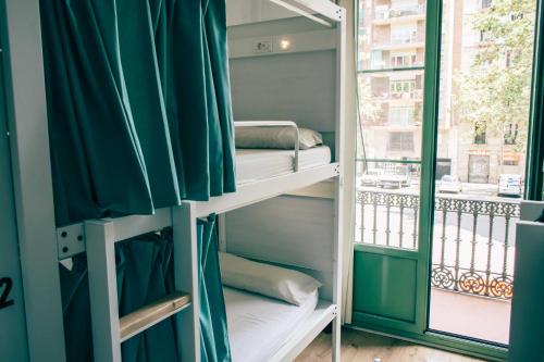 バルセロナにあるブラック スワン ホステルの窓際の二段ベッドが備わる客室です。