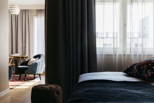 a bedroom with a bed and a window with a chair at Hotel St. George Helsinki in Helsinki