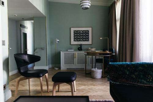 a living room with green walls and a table and chairs at Hotel St. George Helsinki in Helsinki