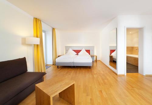 a living room with a bed and a couch at AKZENT Brauerei Hotel Hirsch in Ottobeuren