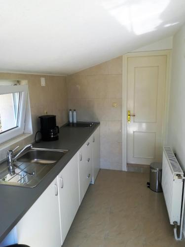 a kitchen with white cabinets and a sink and a door at Olive grove in Vodice