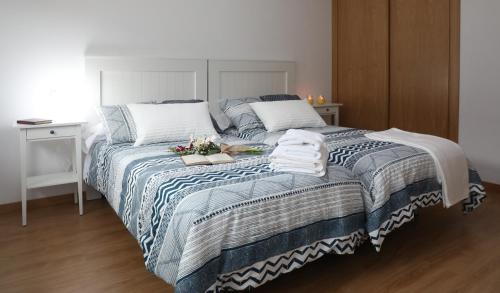 a bedroom with a bed with a blue and white comforter at Chalet Vacacional Salnés Sur con PISCINA in Cambados