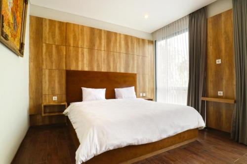 a bedroom with a large bed with a wooden headboard at Villa Prana Jimbaran in Jimbaran