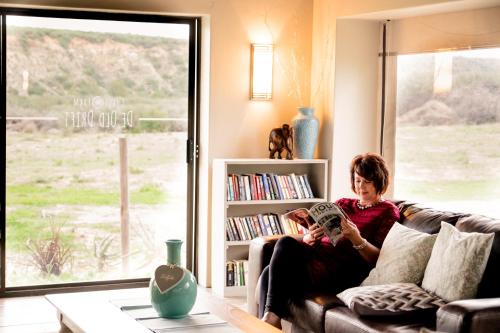 a woman sitting on a couch reading a book at De Old Drift Guest Farm in Addo