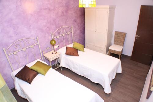 two beds in a room with purple walls at Casa Rural Maria Isabel in Puigmoreno