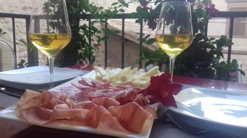 a plate of meat and cheese and two glasses of wine at Hotel Sorella Luna in Assisi