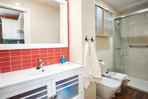 Un baño con lavabo, inodoro y espejo. en Rodrigo de Triana Courtyard by Valcambre, en Sevilla