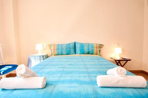 Un dormitorio con una cama azul con toallas. en Rodrigo de Triana Courtyard by Valcambre, en Sevilla