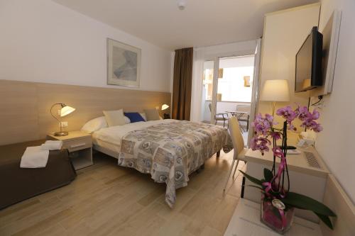 a hotel room with a bed and a table with flowers at Hotel & Apartments Eldorado in Grado