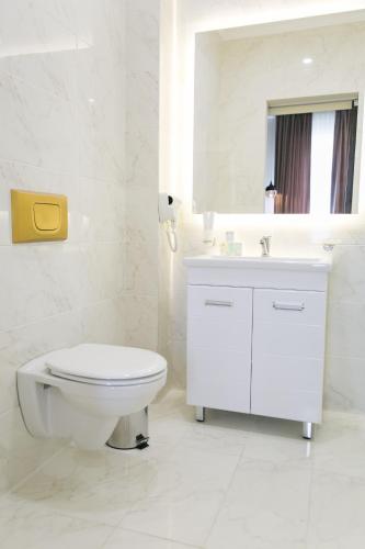 a white bathroom with a toilet and a sink at Ambassador in Almaty