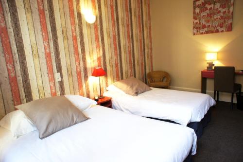 a hotel room with two beds and a desk at Hotel des Alpes in Die