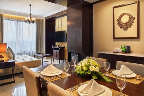 a dining room with a table and a living room at Jambuluwuk Oceano Seminyak Hotel in Seminyak