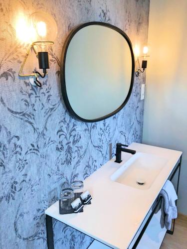 a bathroom with a sink and a mirror on a wall at La Maison Gervaiserie & Spa in Réville