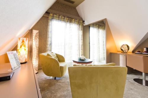 a living room with a yellow chair and a couch at Le Domaine Des Chevaliers De Malte in Villedieu-les-Poëles
