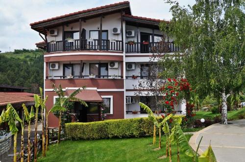 a pink and white building with a balcony at Makaza Complex in Momchilgrad