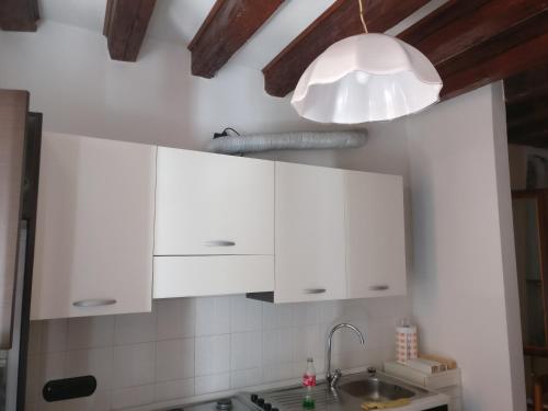 une cuisine avec des armoires blanches et un luminaire dans l'établissement alla lista, à Venise