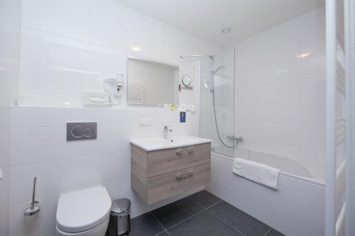 a white toilet sitting next to a bath tub in a bathroom at Kings Inn City Hostel in Alkmaar