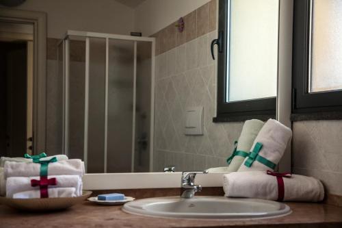 ein Badezimmer mit einem Waschbecken, einem Spiegel und Handtüchern in der Unterkunft Sardinian Gallery Temo in Bosa