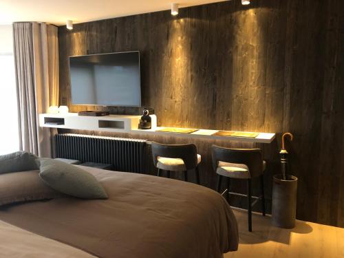 a bedroom with a bed and a bar with a television at Le Sable Doux 4D in Middelkerke
