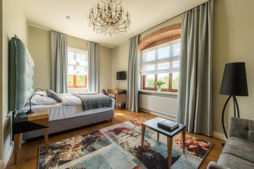 a bedroom with a bed and a couch and a chandelier at Pałac Warlity in Olsztynek