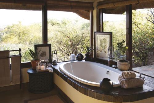 a bath tub in a room with a large window at Tuningi Safari Lodge in Madikwe Game Reserve