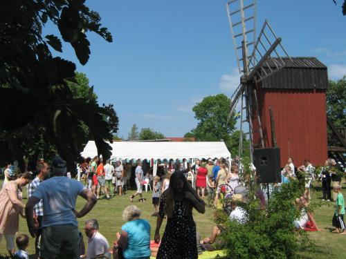 a crowd of people in a field with a windmill at Kvarngården Natur Resort in Byxelkrok