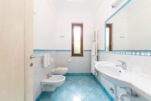 a bathroom with two sinks and a toilet at La Capannina - Hotel & Apartments in Ischia