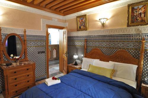 a bedroom with a blue bed and a mirror at Dar Al Madina Al Kadima in Fès