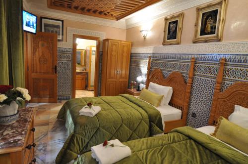 a hotel room with two beds and a television at Dar Al Madina Al Kadima in Fès