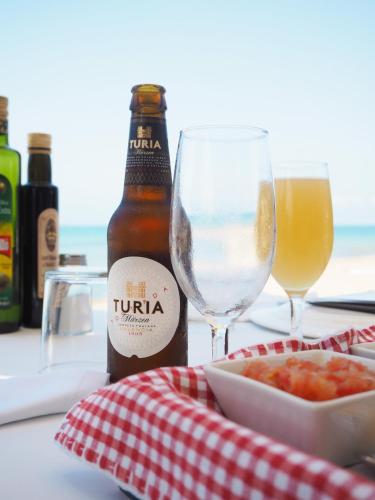 a table with a bottle of beer and a bowl of food at Hotel Noguera Mar in Denia