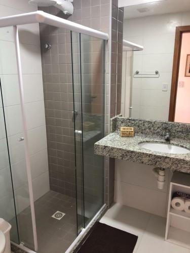 a bathroom with a glass shower and a sink at Village Beira Mar em Itacimirim in Itacimirim
