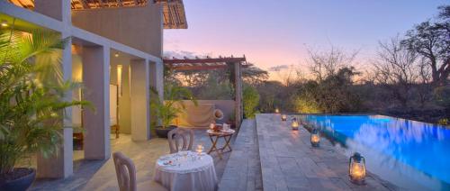a patio with a table and chairs next to a swimming pool at Finch Hattons Luxury Tented Camp in Tsavo