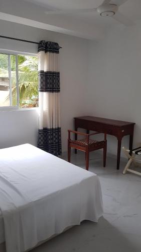 a bedroom with a bed and a table and a window at Mount View Inn in Kandy