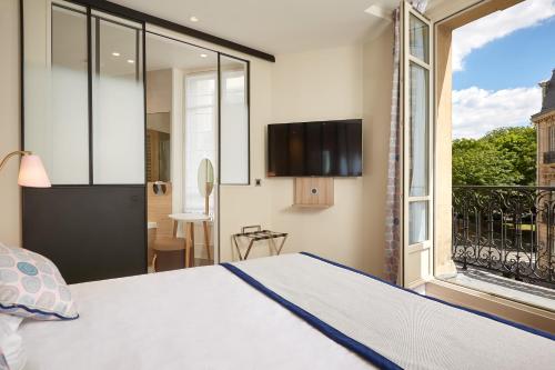 - une chambre avec un lit et une grande fenêtre dans l'établissement Hôtel de Sévigné, à Paris